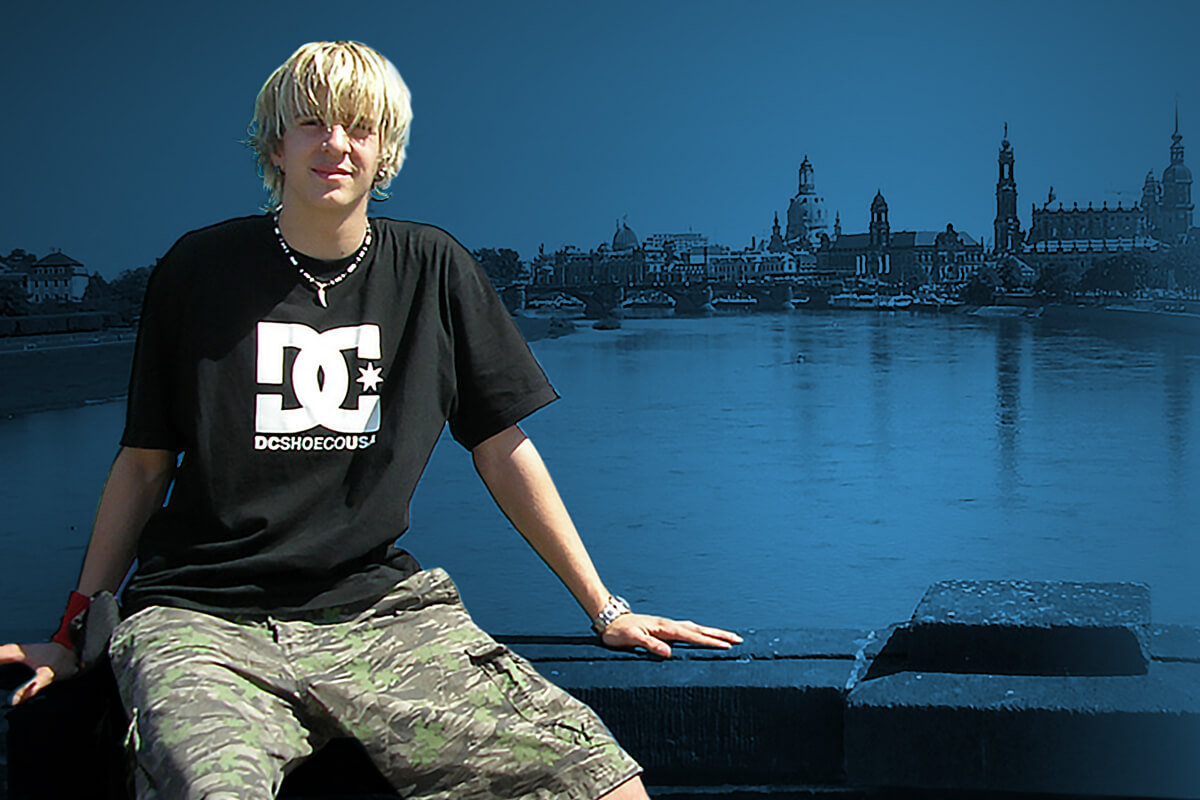 Marty als Jugendlicher sitzt auf einer Mauer am Elbufer, dahinter die Silhouette der Dresdner Altstadt