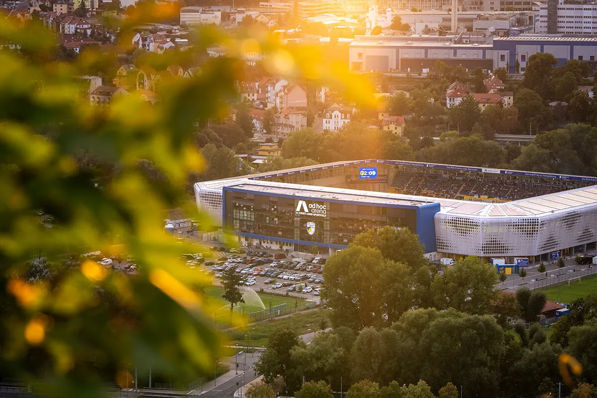 Luftaufnahme der ad hoc arena im Abendlicht, gerahmt von Herbstlaub