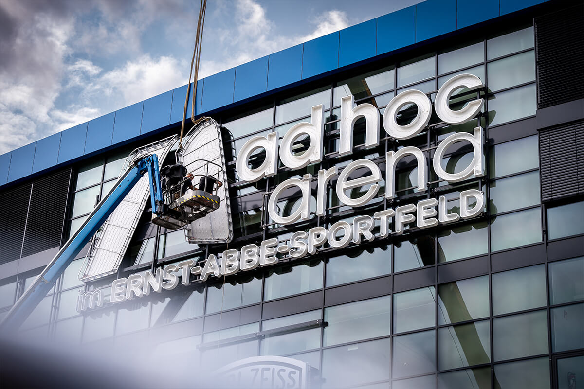 Der Schriftzug ad hoc arena im Ernst-Abbe-Sportfeld wird montiert