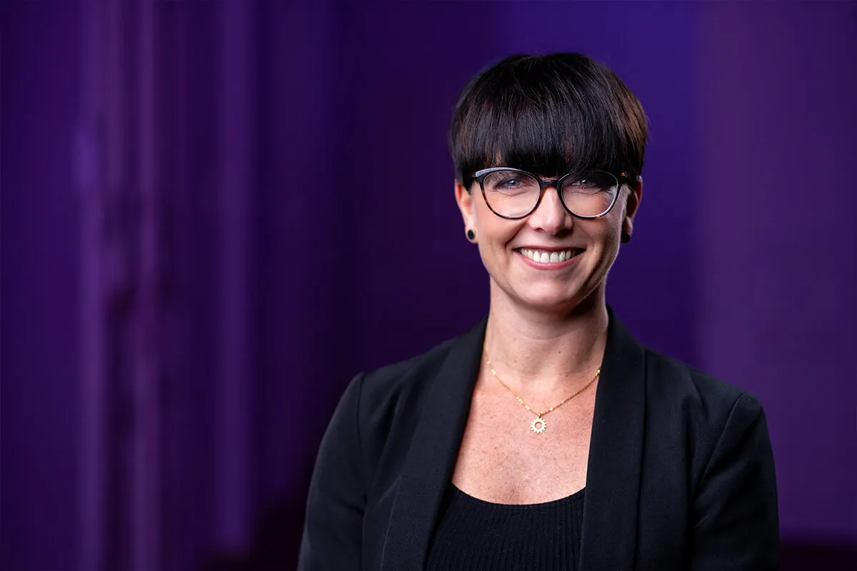 Headshot einer Mitarbeiterin vor violettem Lichthintergrund