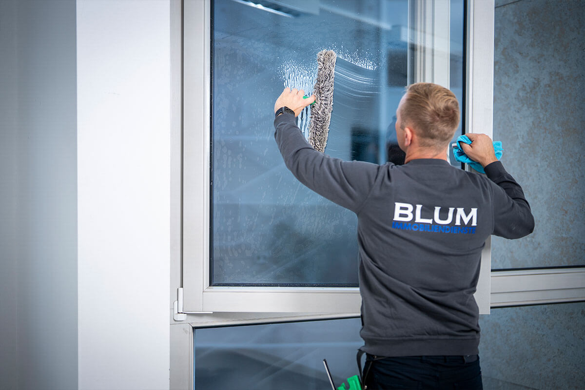 Glasreinigung im Treppenhaus, auf dem Rücken der Schriftzug Blum Immobiliendienste