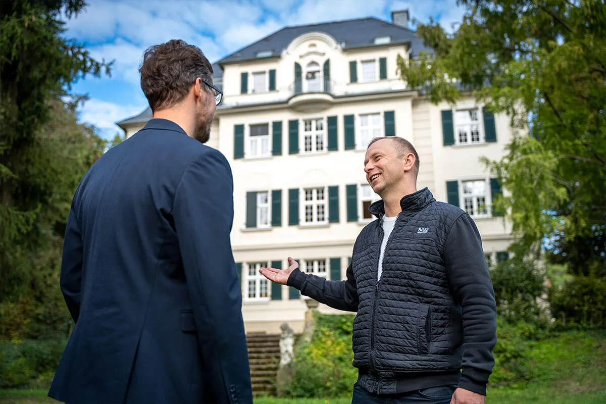 Zwei Männer im Gespräch vor einem historischen Gebäude für Blum Immobiliendienste