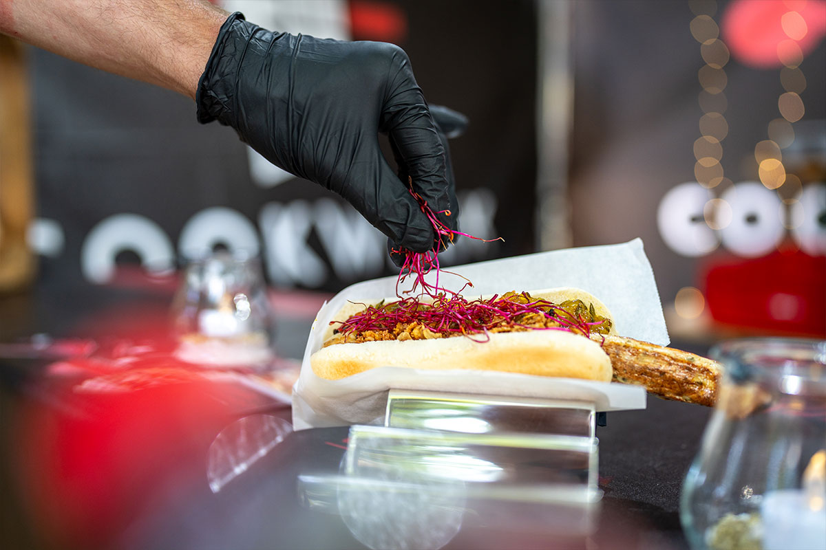 Beim Anrichten wird ein belegtes Brötchen mit roten Sprossen garniert