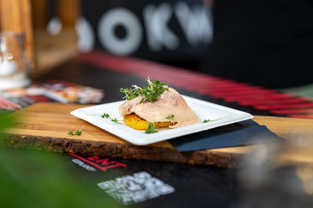 Fischfilet auf Kartoffelrösti mit Kresse, angerichtet auf einem Holzbrett