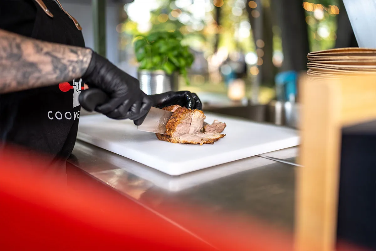 Küchenmitarbeiter tranchiert einen Braten am Cateringstand