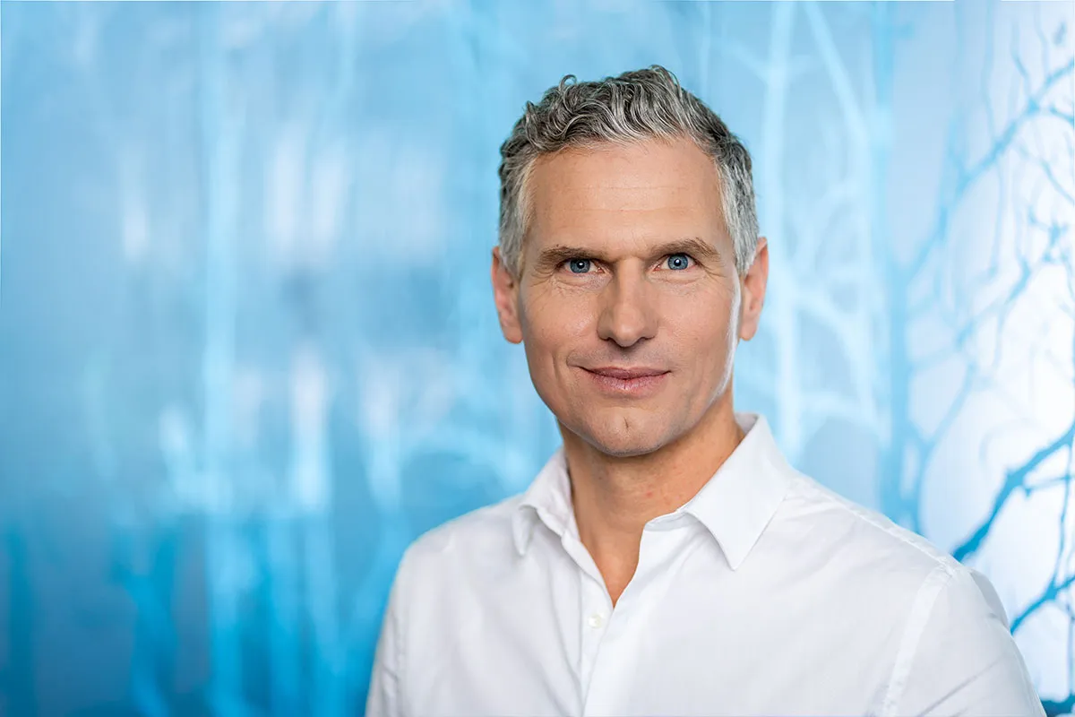 Headshot eines Mitarbeiters im weißen Hemd vor blauem Lichthintergrund