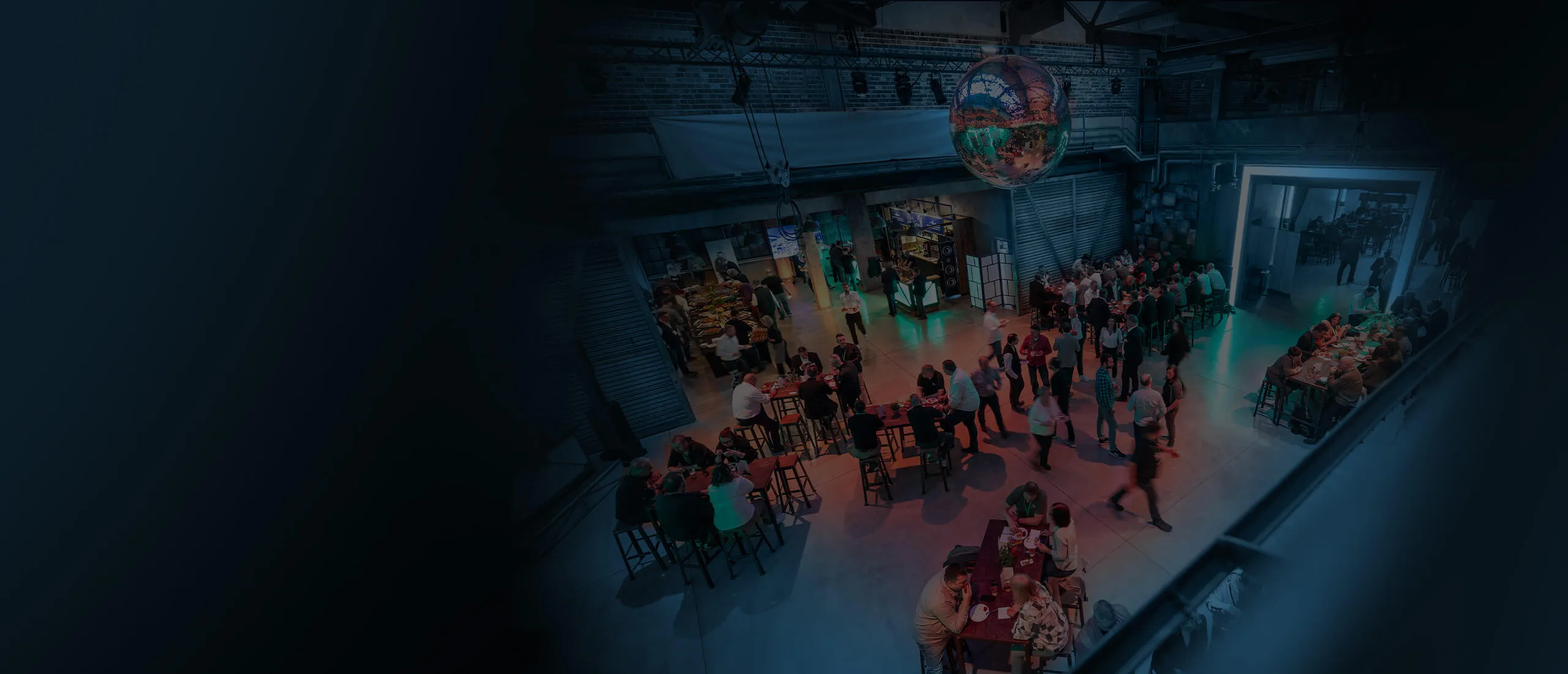 Abendveranstaltung in einer Industriehalle mit Discokugel und Stehtischen