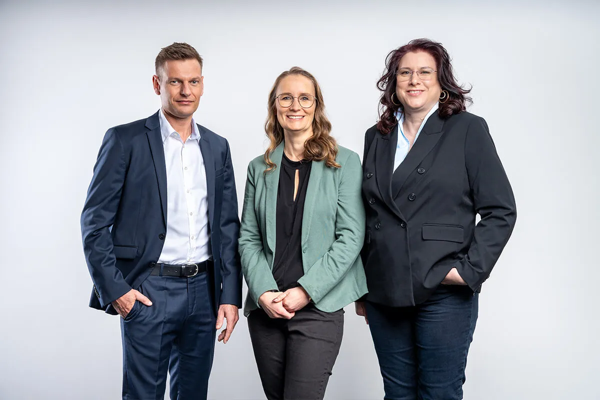 Dreiköpfiges Team von Inway Systems vor weißem Hintergrund