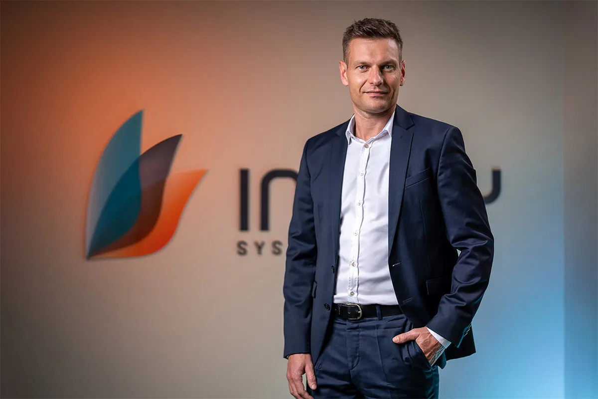 Mitarbeiter von Inway Systems im Anzug vor der Logowand des Unternehmens