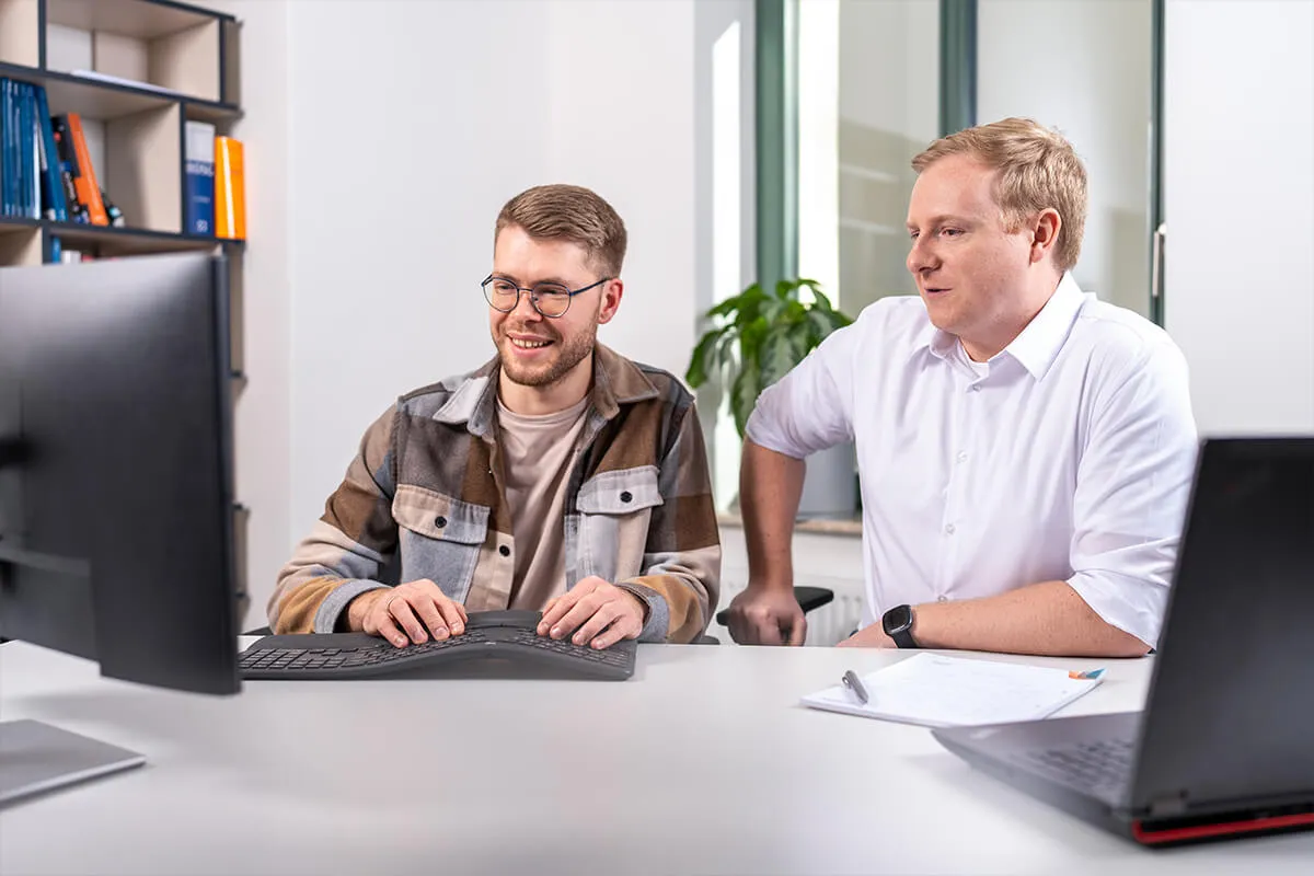 Zwei Kollegen arbeiten gemeinsam am Bildschirm im Büro