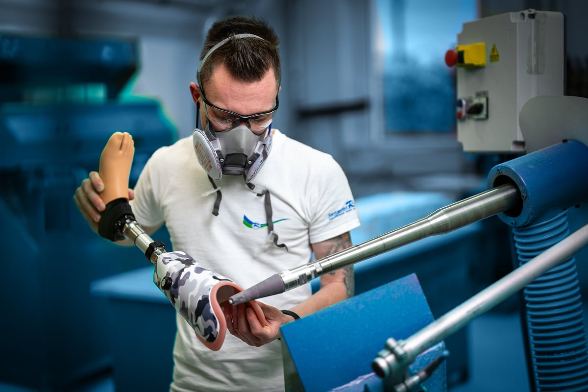 Orthopädietechniker mit Atemschutz arbeitet an einem Beinprothesenschaft