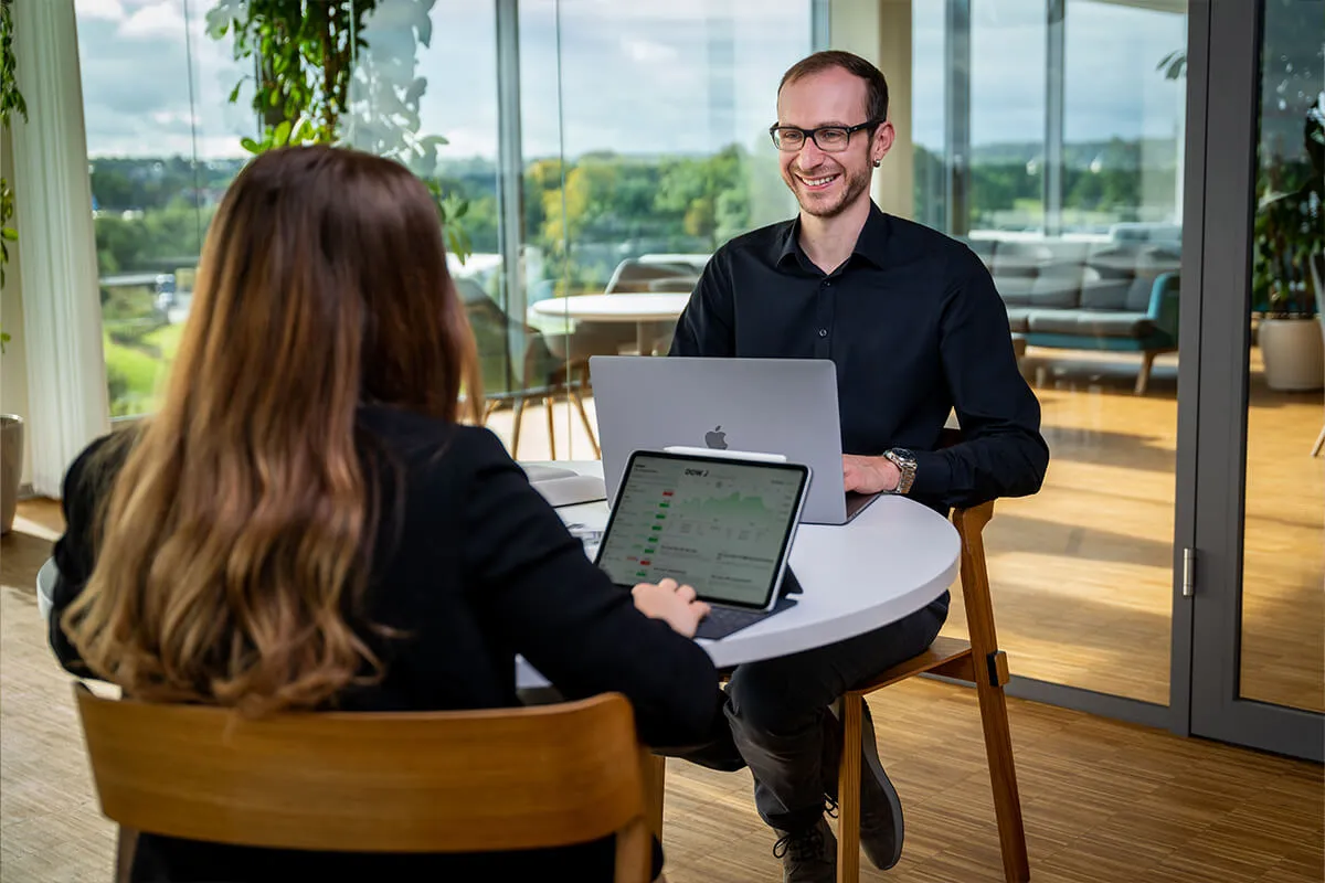 Mitarbeiter zeigt einer Kollegin etwas auf dem MacBook