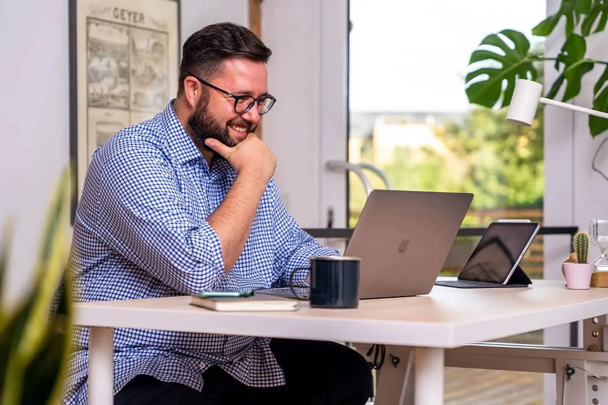 Mitarbeiter im Homeoffice am MacBook mit zusätzlichem Tablet