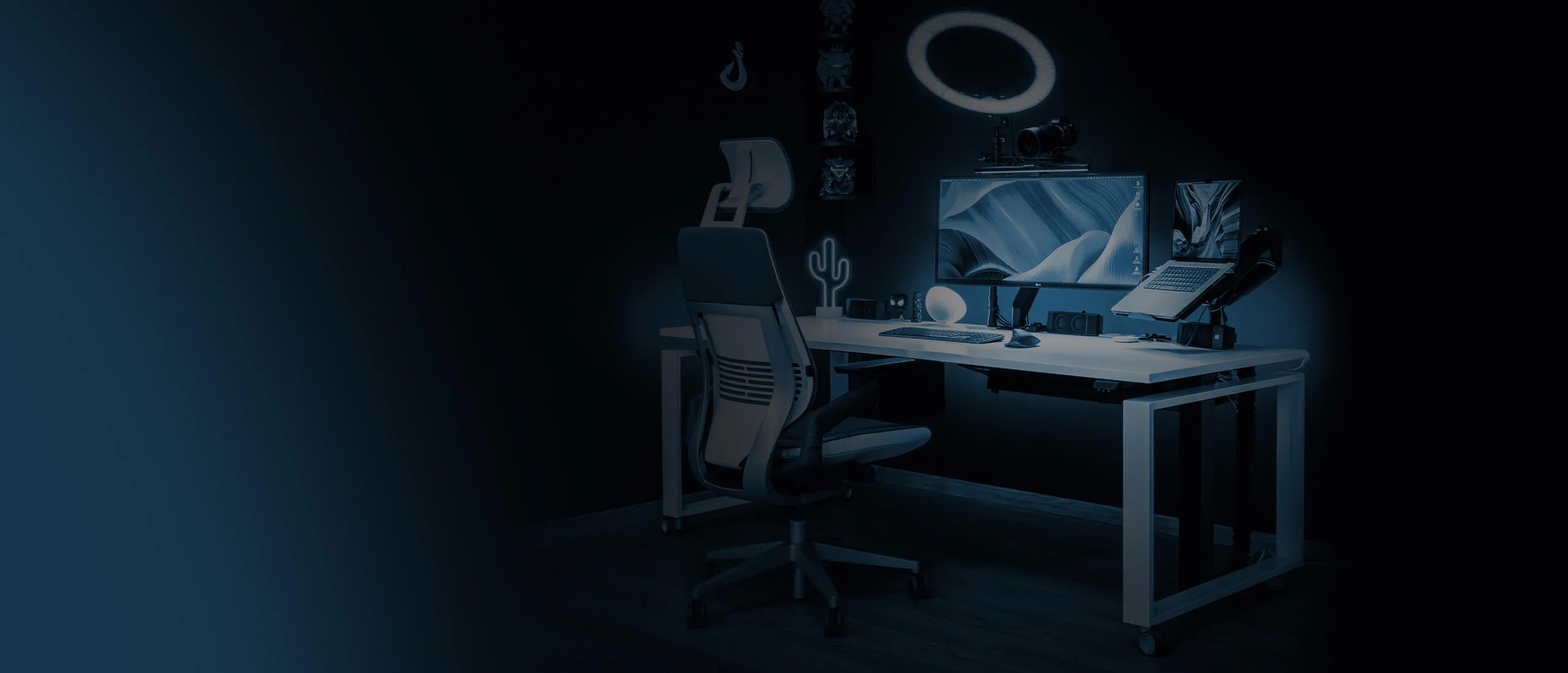 Arbeitsplatz von image creator mit Monitor, Ringlicht und Kamerazubehör in blauem Licht