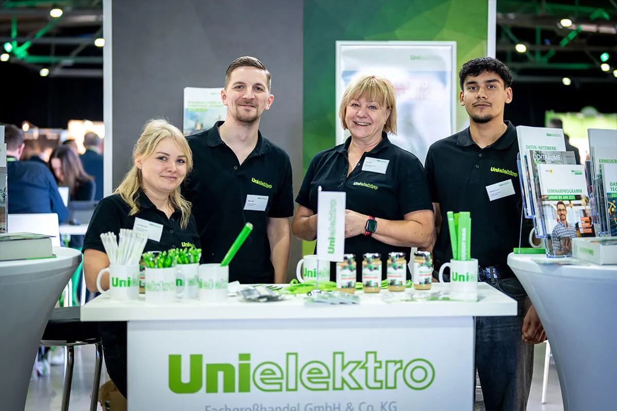 Vierköpfiges Standteam hinter dem Messetresen