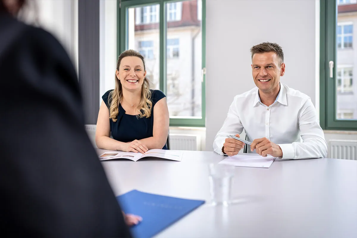 Zwei Mitarbeitende im Besprechungsraum an einem hellen Konferenztisch