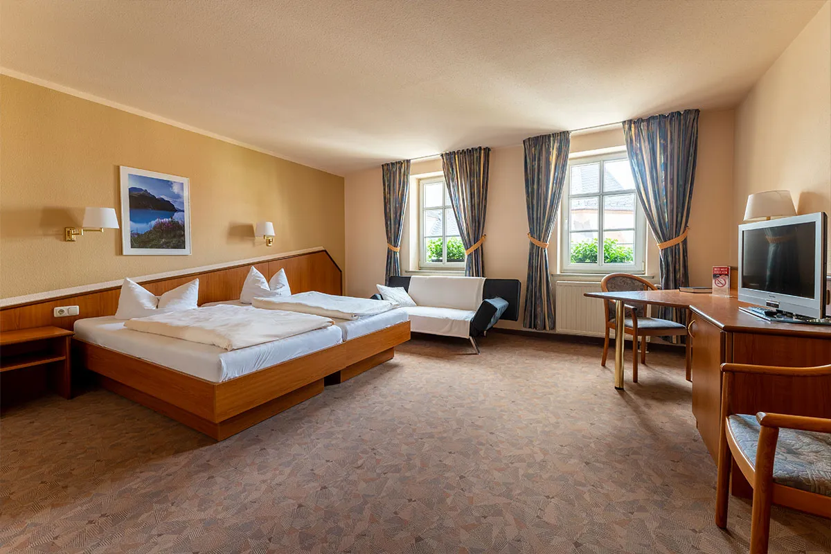 Hotelzimmer mit Doppelbett, Schreibtisch und Fernseher