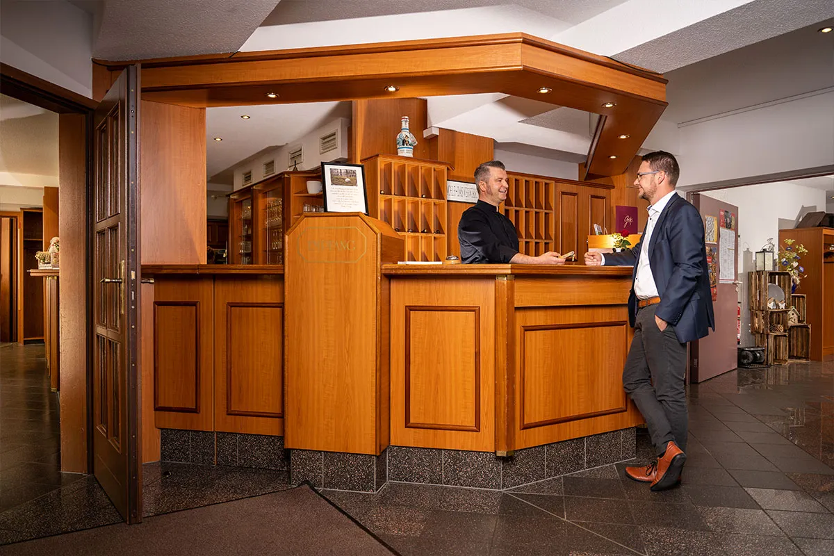Gast im Gespräch mit einem Mitarbeiter an der Hotelrezeption