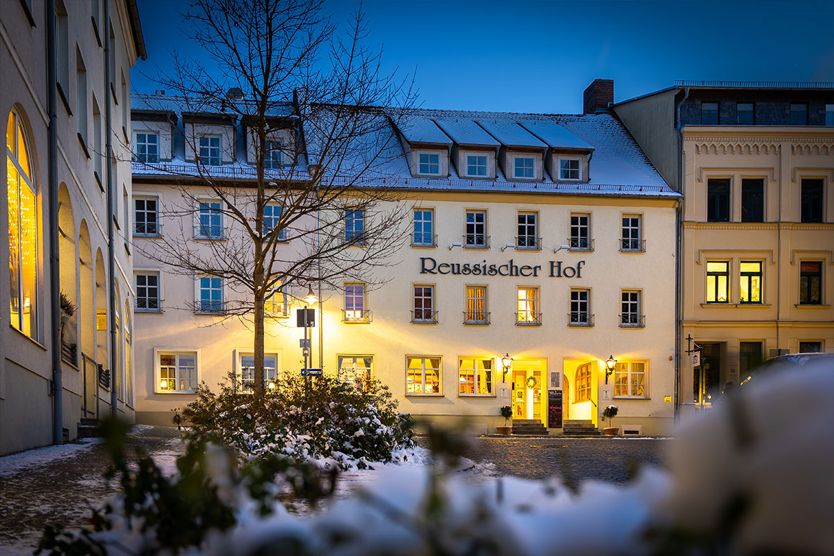 Die beleuchtete Fassade des Hauses an einem Winterabend im Schnee