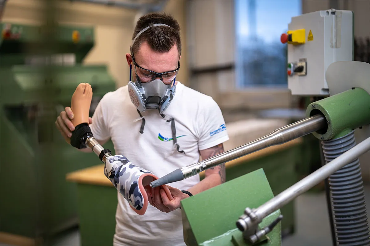 Orthopädietechniker mit Atemschutz bearbeitet einen Prothesenschaft