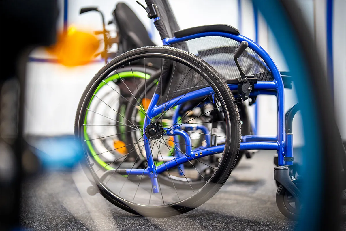 Detailaufnahme: Rad und Rahmen eines blauen Rollstuhls