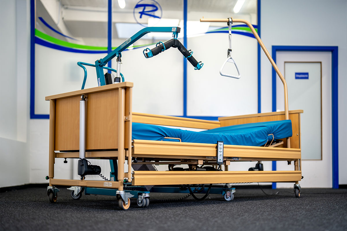 Pflegebett mit Aufrichter und Patientenlifter im Ausstellungsraum