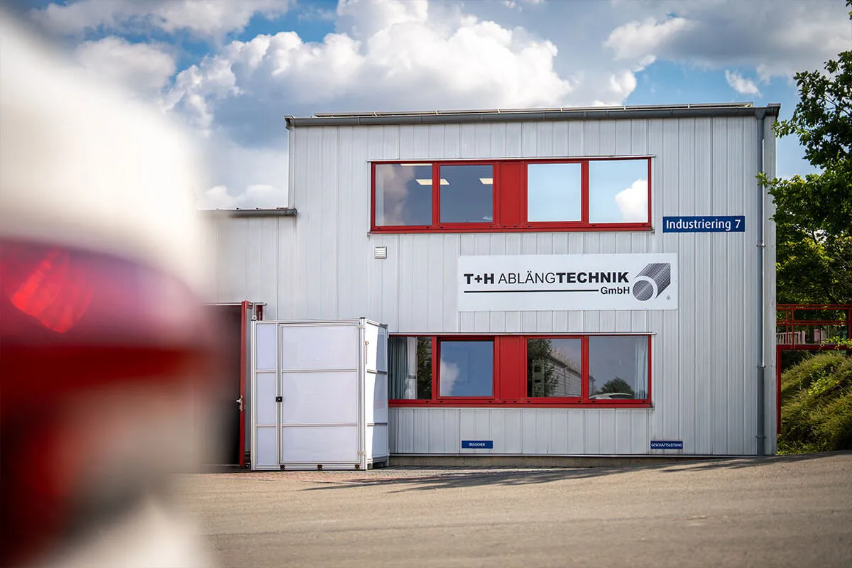 Firmengebäude der T+H Ablängtechnik GmbH mit rotem Auto im Vordergrund