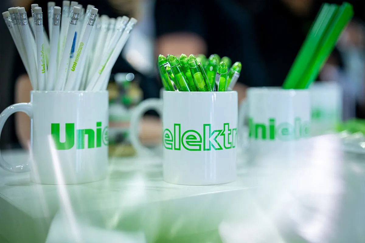 Detailaufnahme: Werbeartikel und Tassen mit dem Logo von UNI ELEKTRO