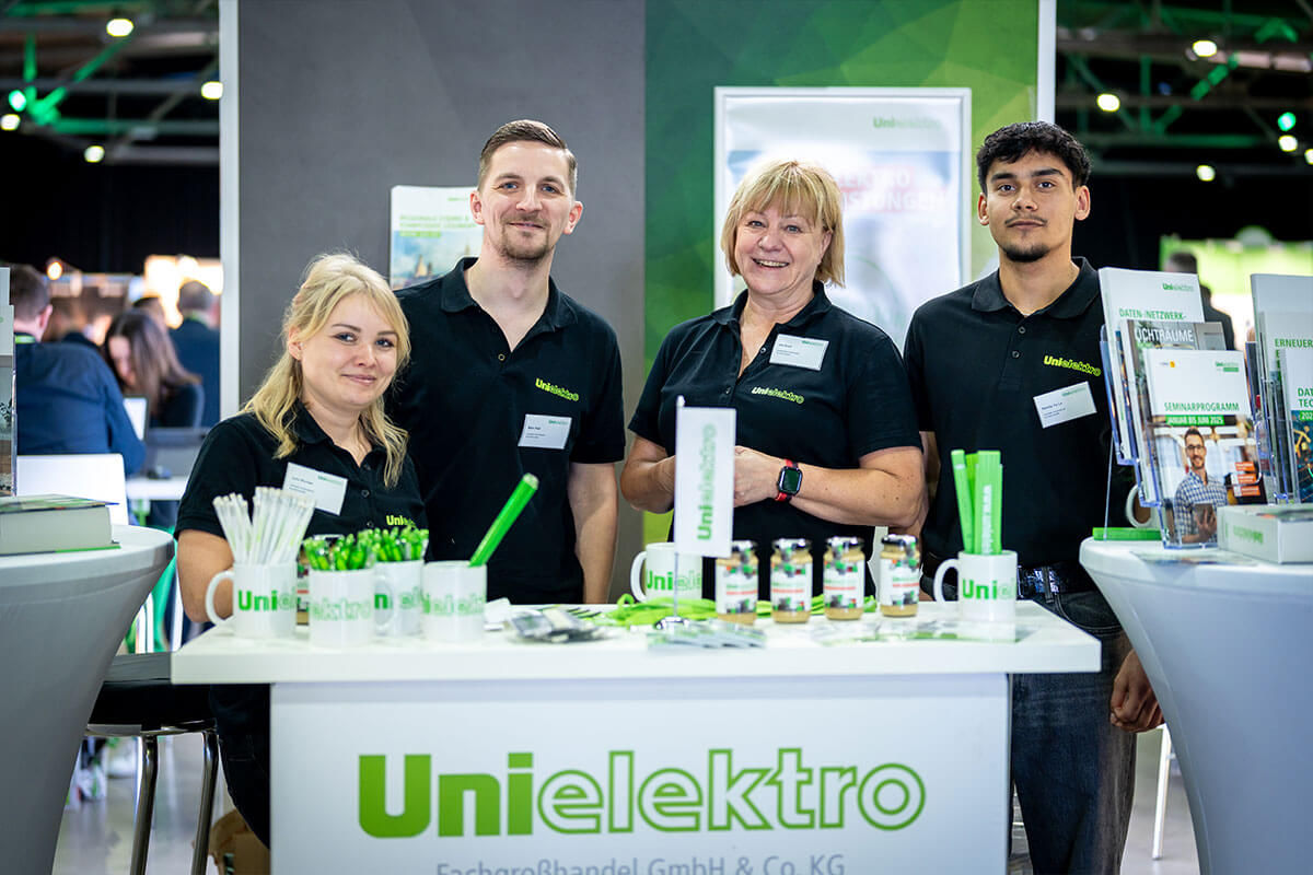 Vier Mitarbeiterinnen und Mitarbeiter am Messestand hinter der Infotheke